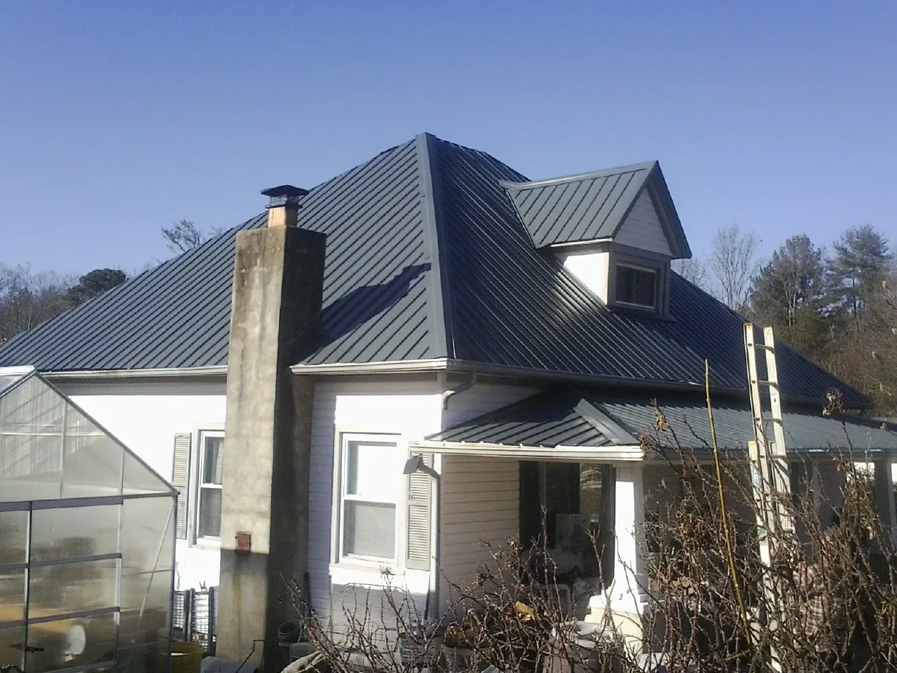 Dark blue standing seam metal roof on a white farmhouse with dormer — Slate & Tile Roof Repair by Roofing Brothers in Stoughton