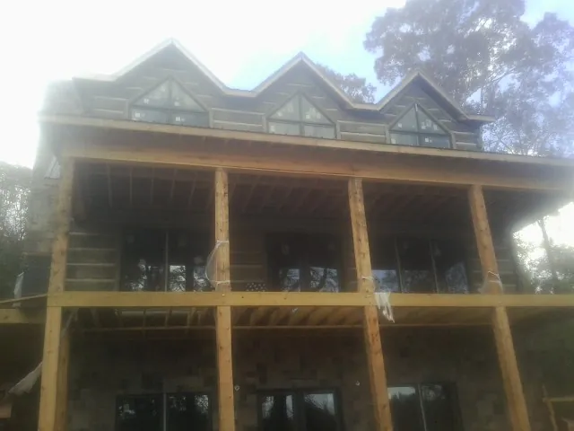 Dormers and porch framing on a large log home under construction — Roof Coating work by our crew in Stoughton