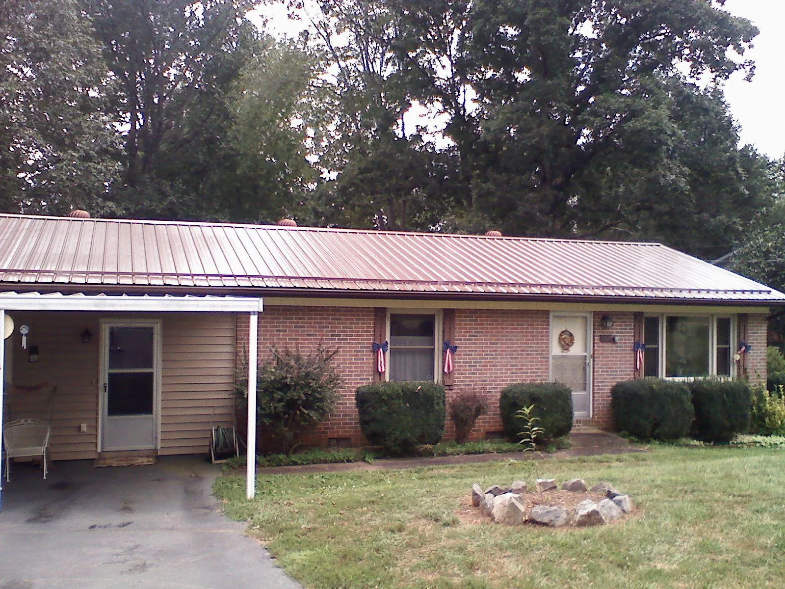 Bronze metal roof and carport on a brick ranch home — Roof Repair work by our crew in Stoughton