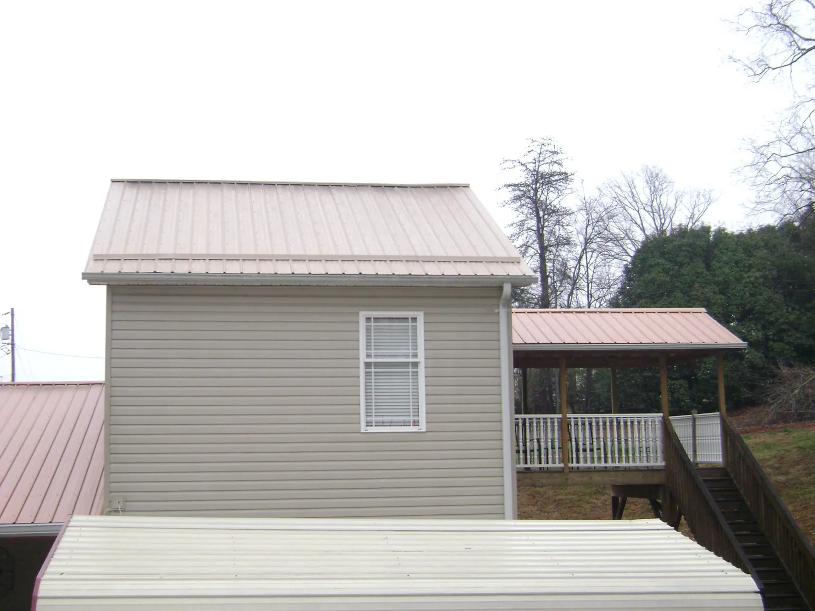 Tan metal roofs on a two story addition and attached porch, from a Roof Replacement job in Stoughton